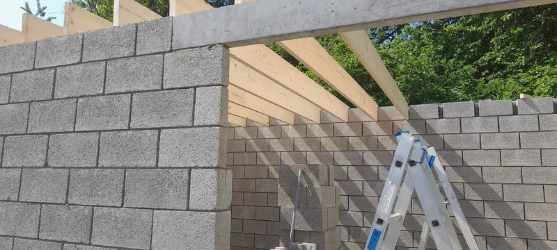 Murs en blocs de béton et charpente posée sur une extension